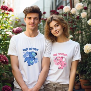 May include: Two white t-shirts featuring cartoon character designs. One shirt says "Her Stitch" with a blue character and blue floral accents. The other says "His Angel" with a pink character and pink floral accents. The shirts are worn by a couple.