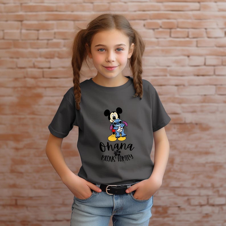 May include: A charcoal gray t-shirt featuring a graphic of Mickey Mouse and Stitch hugging. The text "Ohana means family" is printed below the characters. The shirt is worn by a young person.