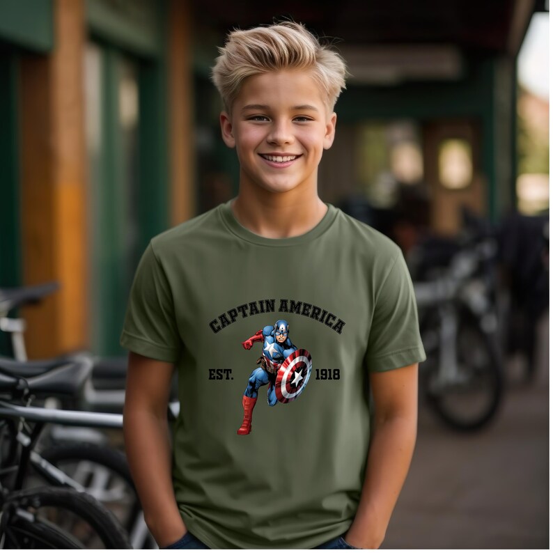 Pu&ograve; includere: T-shirt verde oliva con la scritta "CAPTAIN AMERICA" e l'immagine di Captain America. Sotto c'&egrave; la scritta "EST. 1918". La maglietta &egrave; a maniche corte e ha un girocollo.