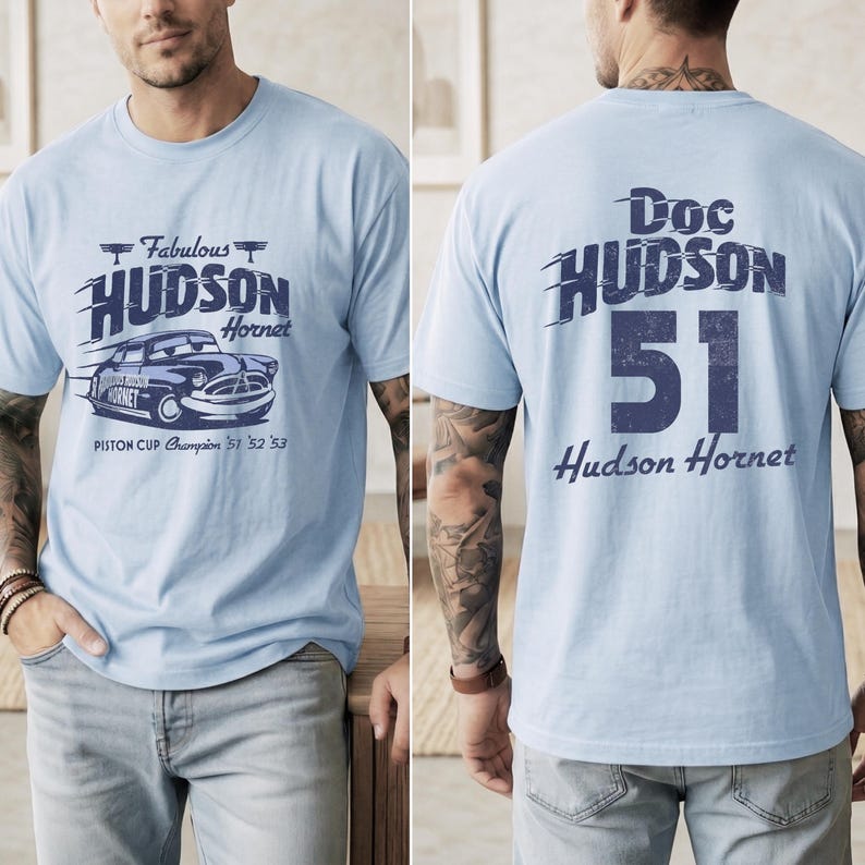 May include: Light blue t-shirt featuring a graphic of the Hudson Hornet race car with the text "Fabulous Hudson Hornet" and "Piston Cup Champion '51 '52 '53". The back of the shirt displays "Doc Hudson 51 Hudson Hornet".