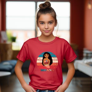 Puede incluir: Camiseta roja con un gr&aacute;fico de estilo vintage de Moana de la pel&iacute;cula de Disney Moana. El gr&aacute;fico presenta a Moana de pie frente a una puesta de sol con el texto "Moana" debajo.