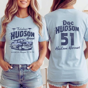 May include: Light blue t-shirts featuring a graphic of a vintage car with the text "Fabulous Hudson Hornet" on the front. The back of the shirt displays "Doc Hudson 51 Hudson Hornet".