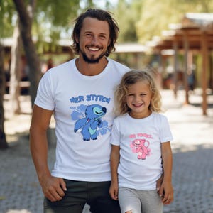 May include: Two white t-shirts with cartoon character graphics. One shirt features a blue character with the text "HER STITCH", and the other has a pink character with the text "HIS ANGEL". The shirts are worn by a man and a young girl.