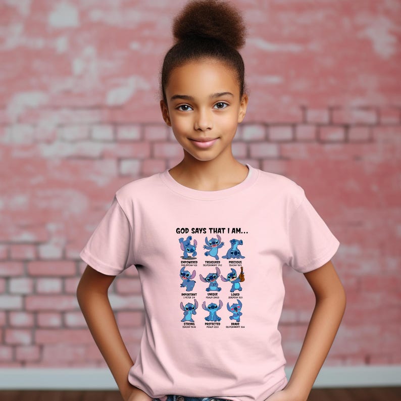 May include: A light pink t-shirt featuring a graphic of the character Stitch from Lilo & Stitch. The graphic includes the text "GOD SAYS THAT I AM..." and various positive affirmations. The shirt is worn by a young person.