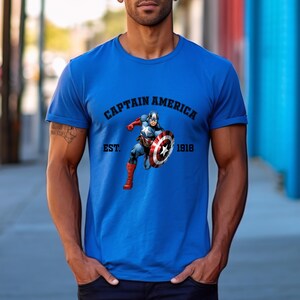 Pu&ograve; includere: Una maglietta blu con una grafica di Captain America con il suo scudo. Il testo "CAPTAIN AMERICA" &egrave; sopra l'immagine, con "EST. 1918" sotto. La maglietta &egrave; di colore blu unito.