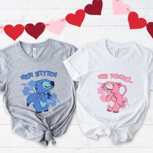 May include: Two t-shirts, one grey and one white, with cartoon character graphics. The grey shirt says "HER STITCH" with a blue Stitch graphic. The white shirt says "HIS ANGEL" with a pink Angel graphic. A garland of red and pink hearts hangs above.