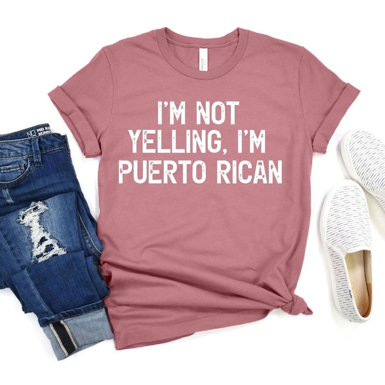 May include: A pink t-shirt with the text "I'm not yelling, I'm Puerto Rican" in white.
