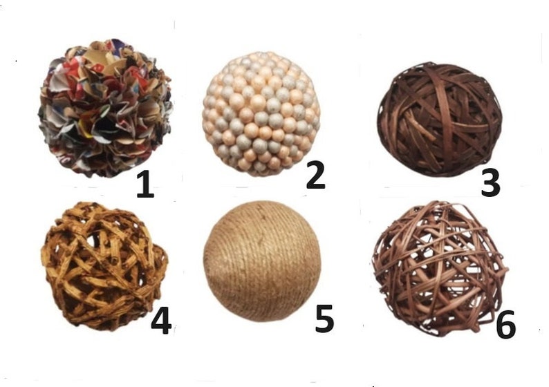 K&ouml;nnte beinhalten: Sechs dekorative Kugeln in verschiedenen Texturen und Materialien. Dazu geh&ouml;ren eine Papierkugel, eine Kugel mit kleinen Perlen, eine Kugel aus geflochtenem Holz, eine geflochtene Kugel, eine Schnurkugel und eine Kugel aus geflochtenen Zweigen.