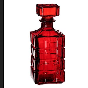 May include: A red glass decanter with a square body and a square stopper. The decanter has a textured surface with a geometric pattern.
