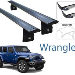 Könnte beinhalten: Ein Satz von zwei schwarzen Dachträger-Querstreben für einen Jeep Wrangler. Die Querstreben sind aus Aluminium und haben eine schwarze Pulverbeschichtung. Die Querstreben sind so konzipiert, dass sie in die Regenrinnen des Jeep Wrangler passen. Das Bild zeigt auch einen blauen Jeep Wrangler.