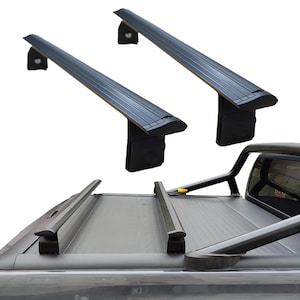 May include: A black roof rack system for a truck, comprising two parallel bars with mounting brackets. The image shows the rack fitted on the truck's roof and bed, offering a secure platform for carrying items. The rack is constructed from robust materials.