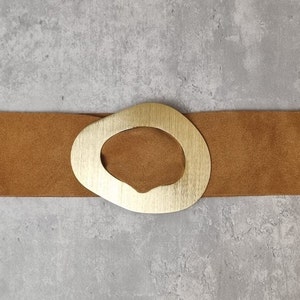 May include: A brown suede belt with a large, gold, oval-shaped buckle.