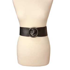 May include: A wide black leather belt with a large, round, textured buckle.
