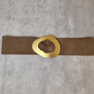 May include: A brown suede belt with a large gold-toned oval buckle.