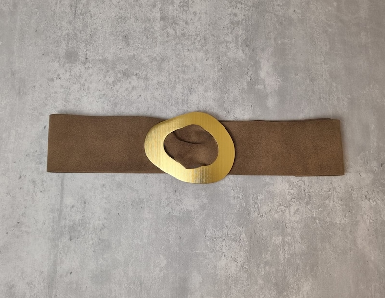 May include: A brown suede belt with a large gold-toned oval buckle.