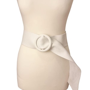May include: A white leather belt with a large, round, white buckle. The belt is tied in a knot at the side.