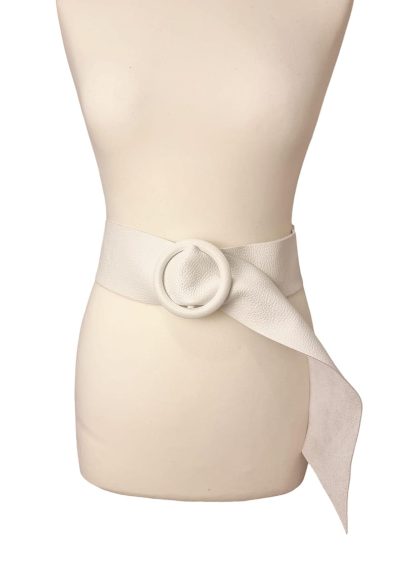 May include: A white leather belt with a large, round, white buckle. The belt is tied in a knot at the side.