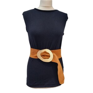 May include: A black sleeveless shirt with a brown belt with a large gold buckle.