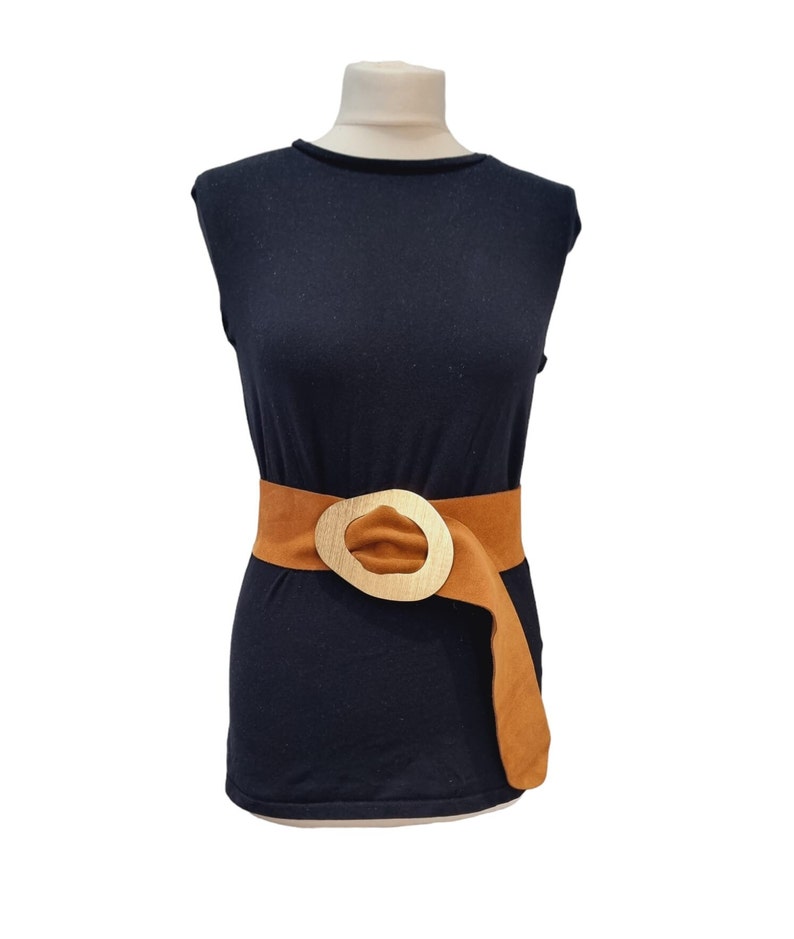 May include: A black sleeveless shirt with a brown belt with a large gold buckle.