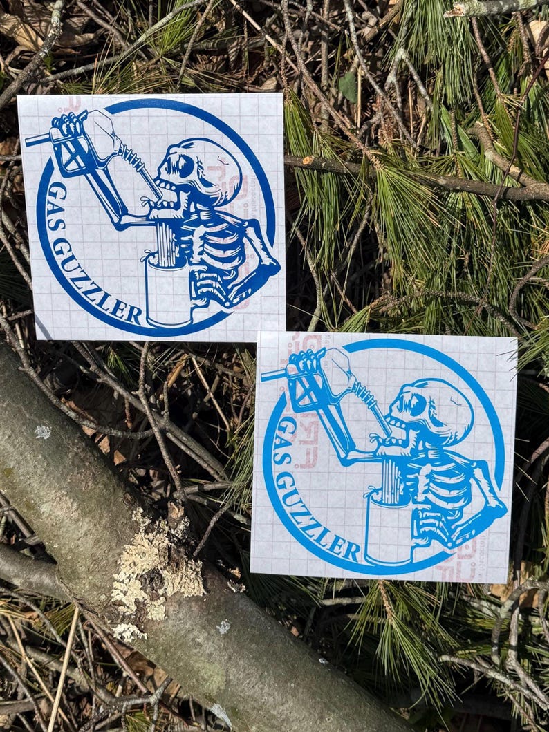 May include: Two square vinyl decals featuring a blue graphic of a skeleton drinking from a gas pump nozzle into a mug. The design is enclosed in a circular border with the text GAS GUZZLER printed along the bottom curve of the circle.
