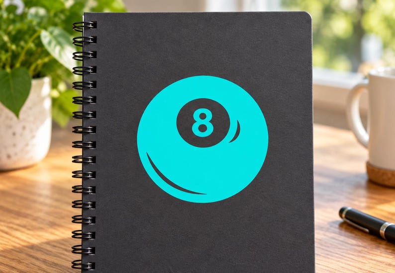 May include: A black spiral-bound notebook featuring a large, bright cyan graphic of an eight ball on the front cover. The design displays a solid cyan circle with a dark gray center containing the white number eight and a curved highlight detail.