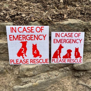 May include: Two white rectangular stickers with red text and dog silhouettes. The text reads "IN CASE OF EMERGENCY PLEASE RESCUE". One sticker shows two dogs with the numbers 2 and 4. The other shows three dogs with the numbers 1, 1, and 1.