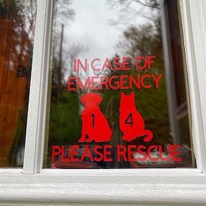 May include: A window with a red decal that reads "IN CASE OF EMERGENCY PLEASE RESCUE" with silhouettes of a dog and cat, and the numbers 1 and 4. The window is framed in white.