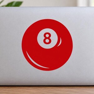 May include: A circular vinyl sticker featuring a solid red billiard ball design with a white center circle containing the number 8 in red. The sticker is applied to the center of a silver laptop lid, displaying a clean and simple graphic aesthetic.