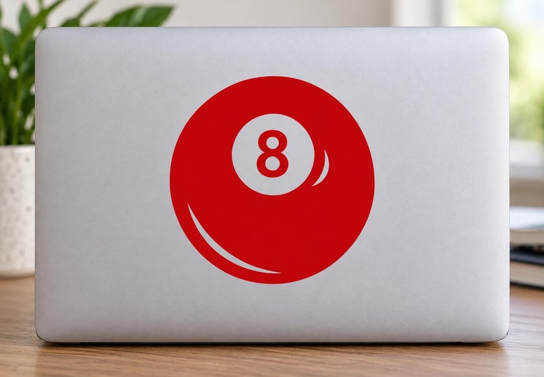 May include: A circular vinyl sticker featuring a solid red billiard ball design with a white center circle containing the number 8 in red. The sticker is applied to the center of a silver laptop lid, displaying a clean and simple graphic aesthetic.