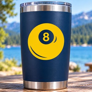 May include: A navy blue stainless steel tumbler featuring a yellow graphic of an eight ball with the number eight centered in a dark blue circle. The tumbler has a metallic silver rim at the top and a matching metallic silver base at the bottom.