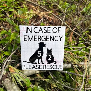 May include: A white square sign with the text "IN CASE OF EMERGENCY" above a black silhouette of a dog and cat. The dog has the number "5" and the cat has the number "2". The text "PLEASE RESCUE" is below the animals.