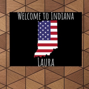 May include: Black and white sign with the text "Welcome to Indiana" and an outline of the state of Indiana filled with the American flag colors. The name "Laura" is written below the state outline.