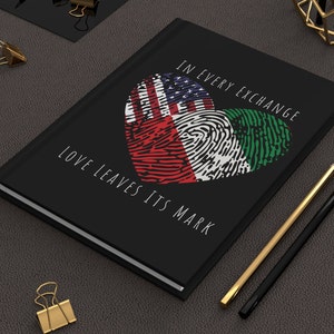 Könnte beinhalten: Schwarzes Notizbuch mit einem herzförmigen Design, das die amerikanische und italienische Flagge zeigt. Der Text "In every exchange love leaves its mark" ist auf dem Cover aufgedruckt.