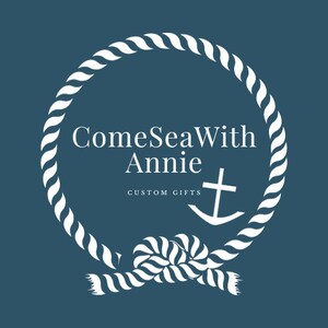 May include: White rope circle with a knot at the bottom. The rope circle has the text "ComeSeaWith Annie" and "CUSTOM GIFTS" inside. A white anchor with a cross at the top is inside the rope circle.