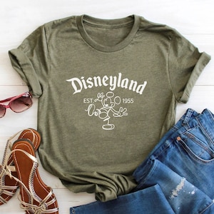 May include: A green t-shirt with a white graphic of Mickey Mouse and the text "Disneyland Est. 1955".