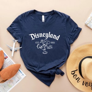May include: A navy blue t-shirt with a white graphic of Mickey Mouse and the text "Disneyland Est. 1955".