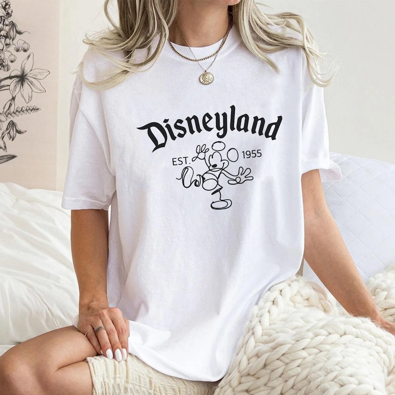 May include: White t-shirt with a black graphic of Mickey Mouse and the text "Disneyland Est. 1955".