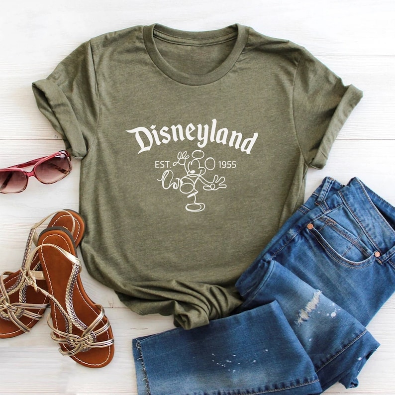 May include: A green t-shirt with a white graphic of Mickey Mouse and the text "Disneyland Est. 1955".