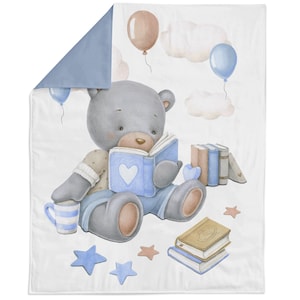 May include: A baby blanket with a watercolour illustration of a grey teddy bear reading a blue book with a heart. The design includes balloons, clouds, books, and stars in soft pastel colours. The blanket is reversible with a solid blue backing.