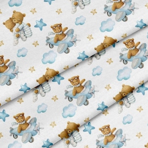 May include: White fabric featuring a repeating pattern of brown teddy bears in aviator gear and blue aeroplanes, clouds, and stars. Some bears are in pyjamas. The design has a watercolour effect.