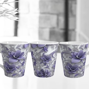 Puede incluir: Tres tazas de cerámica blanca con un diseño floral morado. Las tazas tienen una forma cónica y un asa en el lateral.
