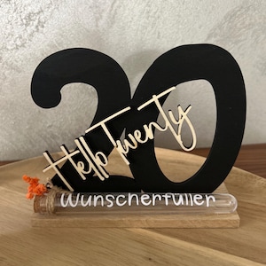 Könnte beinhalten: Schwarze Holzdekoration mit der Zahl 20, den Worten "Hello Twenty" und einem Reagenzglas mit dem Wort "Wunscherfueller". Dekoriert mit kleinen orangefarbenen Blüten.