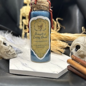 Peut inclure: Une petite bouteille en verre bleu avec un bouchon en liège et un sceau de cire rouge. La bouteille porte une étiquette sur laquelle est inscrit "Draught of Living Death" et "A Powerful Sleeping Draught". L'étiquette comprend également un avertissement qui dit "Avertissement : Le buveur peut paraître temporairement mort."