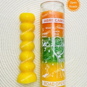 Peut inclure: Une bougie en verre jaune et orange avec le texte "Abre Camino" et "Road Opener" sur l'étiquette. La bougie est entourée d'un fond blanc avec une étoile jaune qui dit "Open Roads".