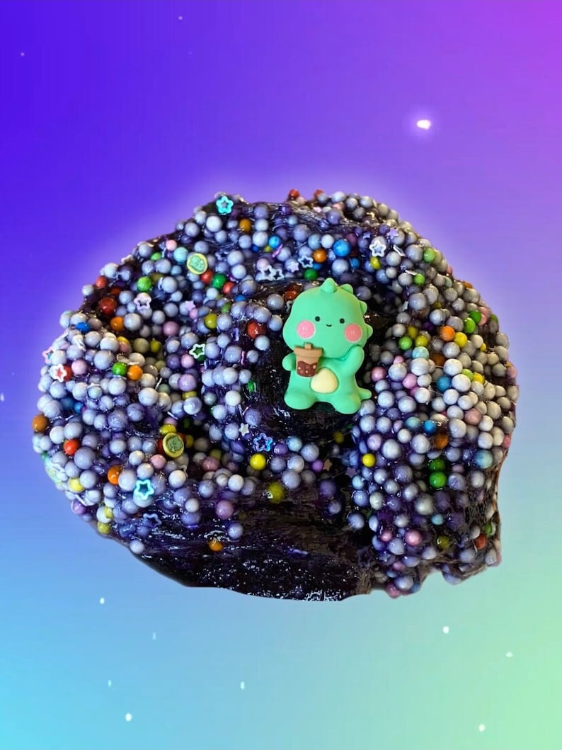 May include: Purple slime with colorful beads and a green cartoon character holding a cup. The slime is in a galaxy-themed background.