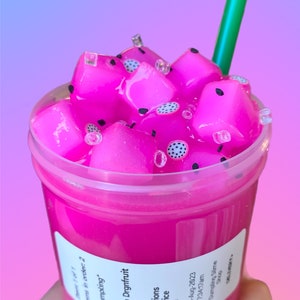 May include: A pink slime with black seeds and white sprinkles in a clear plastic cup with a green straw. The cup has a label that says "Mango Drgnfruit" and "Extra inclusions Extra ice Venti".