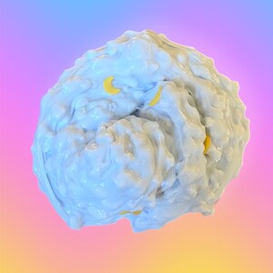 May include: A light blue, textured, blob-like object with yellow crescent moon shapes embedded within. The object has a glossy, reflective surface. The background transitions from blue to pink to yellow.