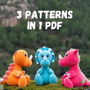 Puede incluir: Tres juguetes de dinosaurios de ganchillo de colores brillantes, naranja, azul y rosa, sentados sobre musgo verde. Cada dinosaurio tiene cuernos blancos y un diseño único. La imagen incluye el texto "3 PATTERNS IN 1 PDF".