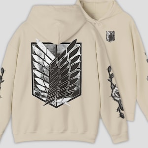Könnte beinhalten: Beigefarbener Kapuzenpullover mit einem großen schwarz-weißen Emblem auf dem Rücken und einem kleineren Emblem auf der Vorderseite. Die Ärmel sind mit Blumen- und Stielmotiven verziert. Der Hoodie hat eine Kapuze mit Kordelzug.