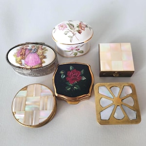 Pode incluir: Uma coleção de seis caixas de joias decorativas. As caixas variam em forma, incluindo oval, redonda e quadrada. Os materiais incluem porcelana, madrepérola e metal, com motivos florais e figurativos.